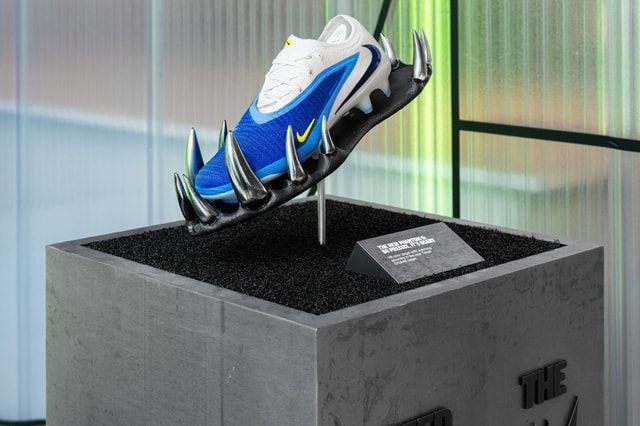 Nike sneaker showcased on a sculptural metal cradle mounted within a concrete plinth display, photographed in a retail/gallery setting.