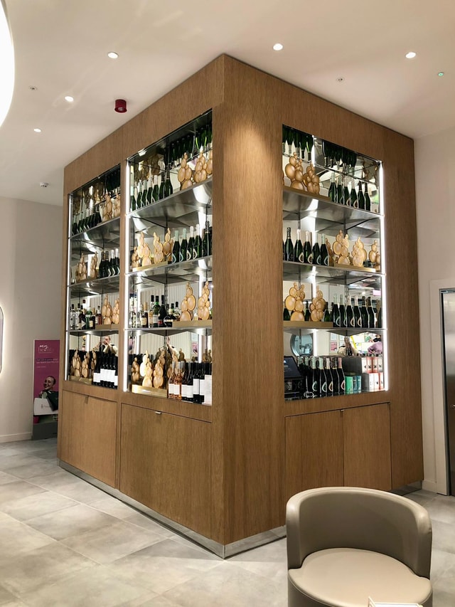Premium in-store champagne display with illuminated mirrored shelving and wood cladding in a retail environment, ideal for merchandising and fixtures.